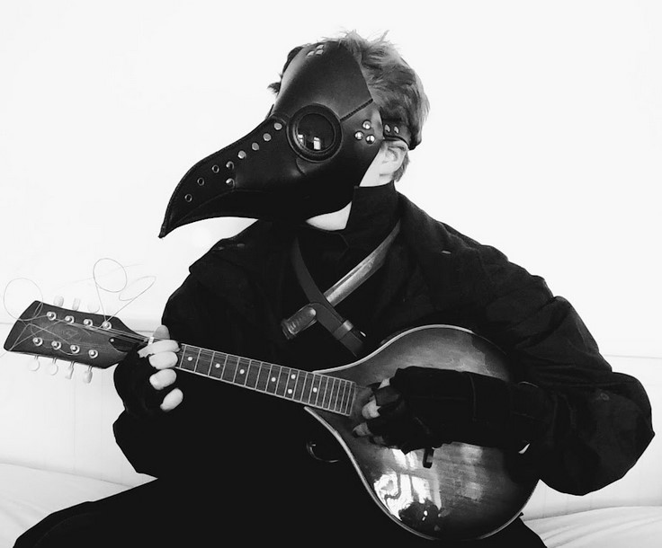 a black and white photo of me in a plague mask playing a mandolin